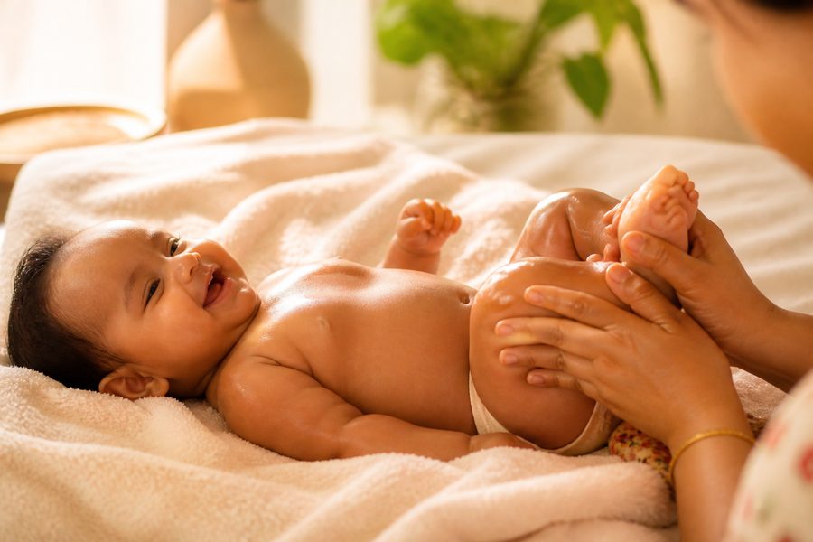 Mother giving baby an oil massage